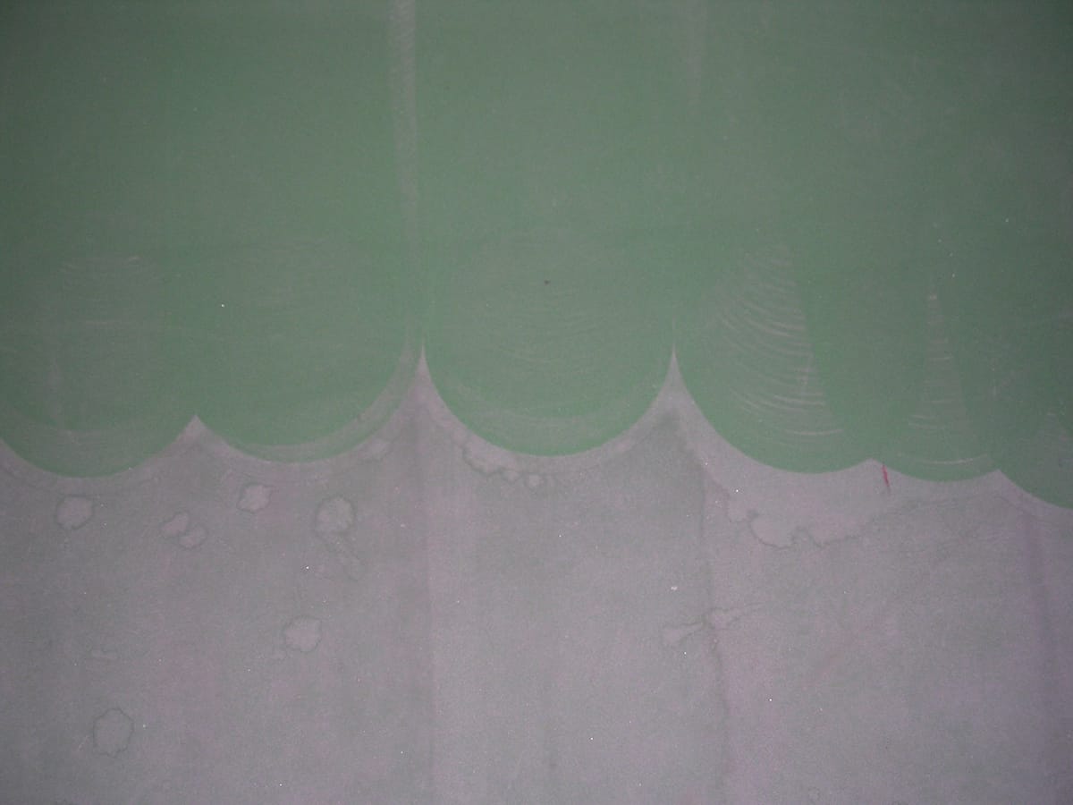 An exterior wall part way through washing, a hard scalloped line dividing the cleaned surface from the soiled one